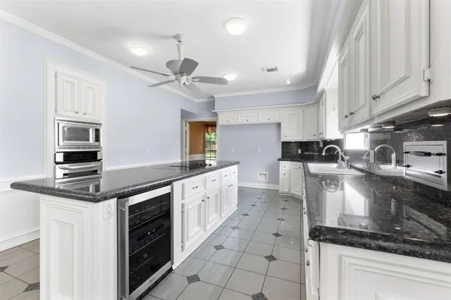 a kitchen with kitchen island granite countertop a sink a counter space appliances and cabinets