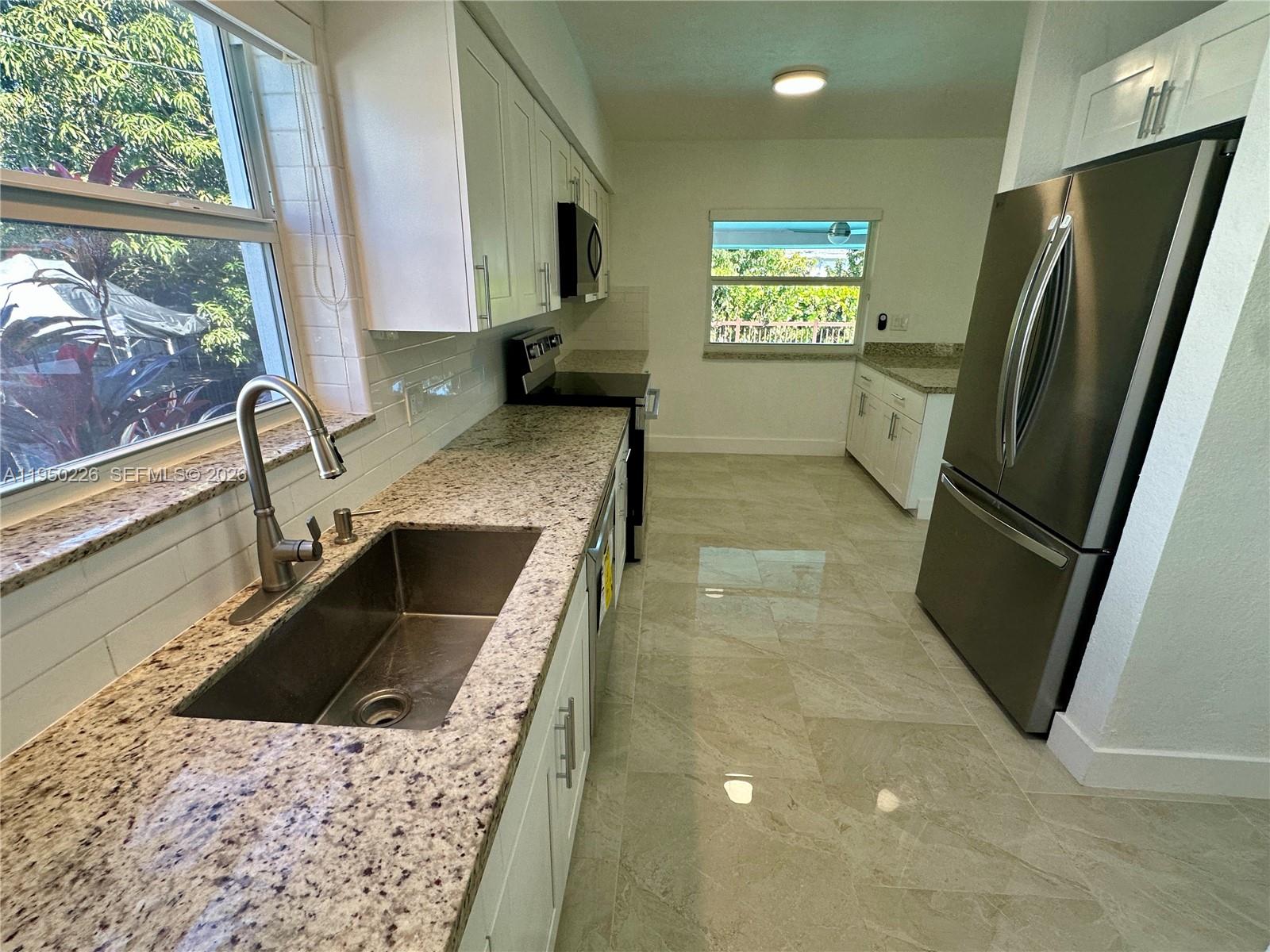 1811 Southwest 83rd Avenue Miami, FL 33155 - Photo 7 of 24 a kitchen with a sink a refrigerator and a stove