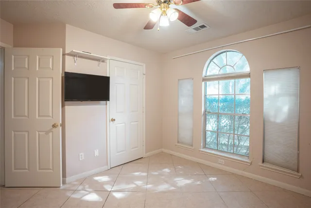 a view of a livingroom with a large window and chandelier fan