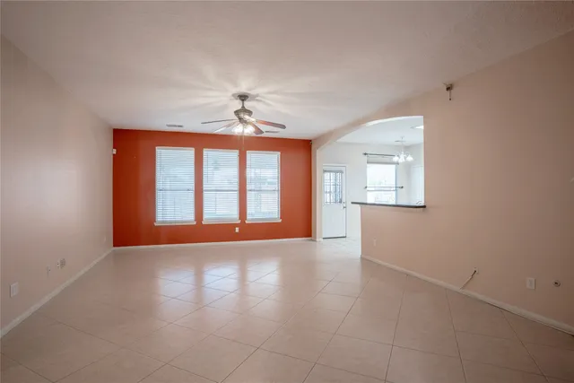 an empty room with windows and chandelier fan
