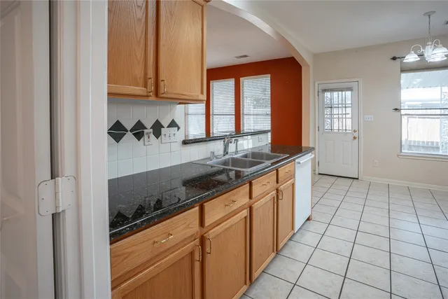 a large kitchen with granite countertop a sink and a white stove next to a window