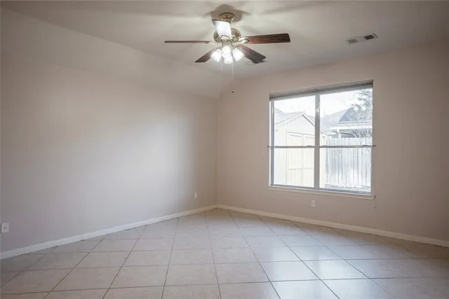 an empty room with chandelier fan and windows