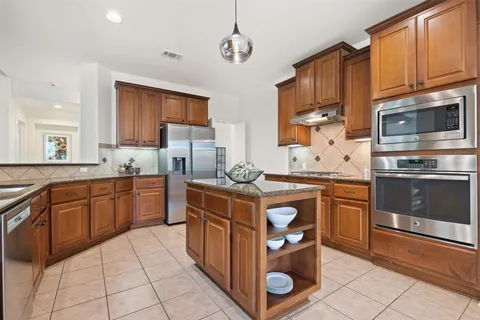 a kitchen with stainless steel appliances granite countertop a stove a sink dishwasher and a microwave oven with cabinets