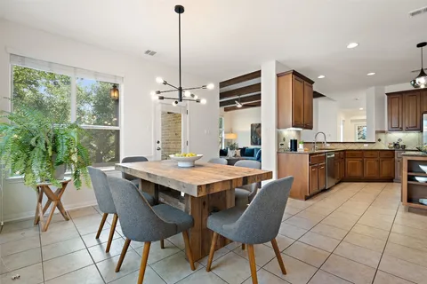 a kitchen with stainless steel appliances kitchen island granite countertop a table chairs and a refrigerator