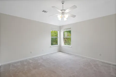 an empty room with chandelier fan and windows