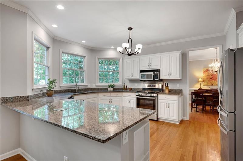 1170 Spring Oak Way Cumming, GA 30041 - Photo 18 of 77 a large kitchen with stainless steel appliances granite countertop a sink dishwasher stove and refrigerator with wooden floor