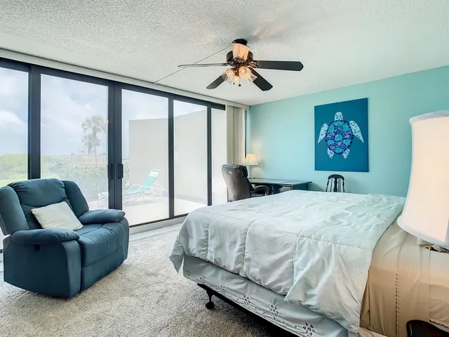 a bedroom with a balcony a bed and a large window