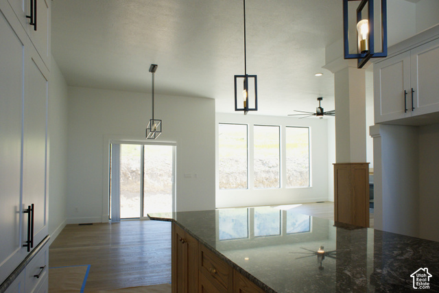 3504 North Sun Dancer Loop Logan, UT 84341 - Photo 10 of 59 Vaulted ceiling, wood-finish flooring, full-height white cabinetry, dark granite countertop, and geometric pendant lighting
