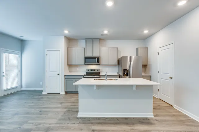 a kitchen with kitchen island a sink a stove a refrigerator and white cabinets