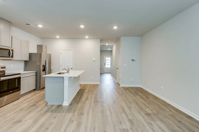 a view of a kitchen with kitchen island a sink wooden floor and stainless steel appliances