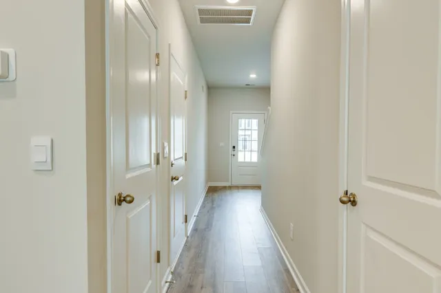 a view of a hallway with wooden floor and a bathroom