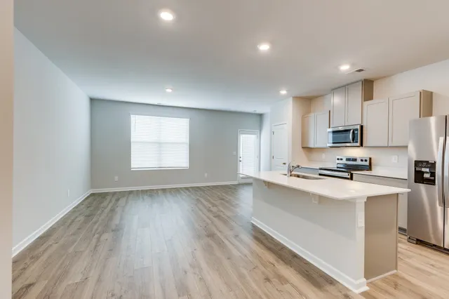 a kitchen with stainless steel appliances a stove top oven a sink a refrigerator and cabinets