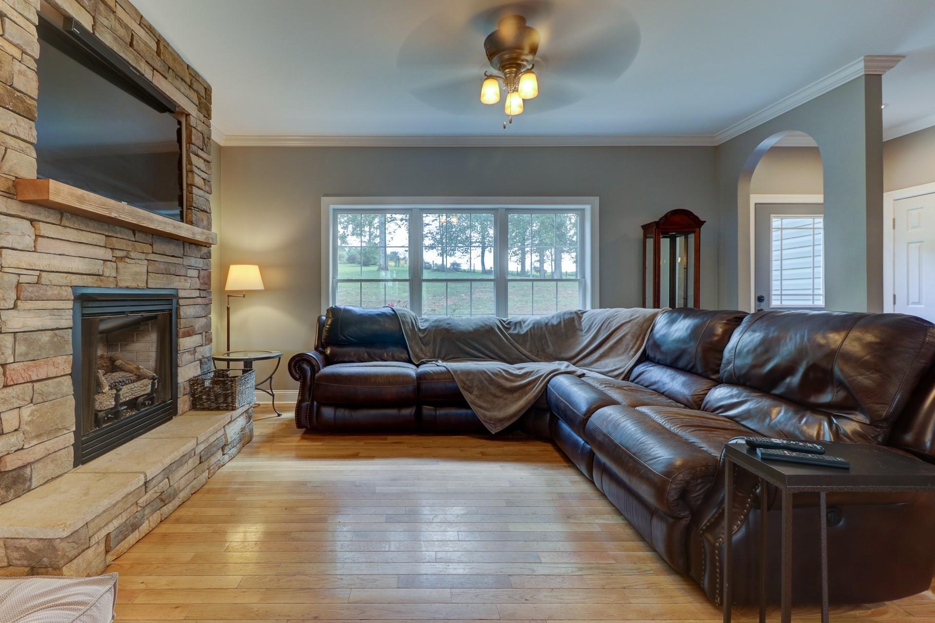 1491 Epperly Mill Road Southwest Floyd, VA 24091 - Photo 4 of 48 a living room with a couch a fireplace a flat screen tv and a large window