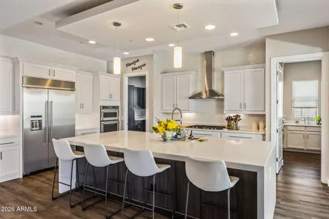 a kitchen with stainless steel appliances kitchen island granite countertop a dining table chairs refrigerator and sink