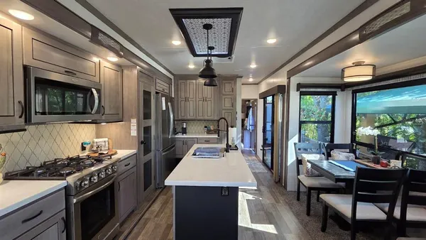a kitchen with stainless steel appliances granite countertop a stove refrigerator and a dining table with large windows