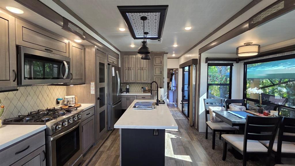 561 Waterway Drive River Ranch, FL 33867 - Photo 3 of 18 a kitchen with stainless steel appliances granite countertop a stove refrigerator and a dining table with large windows