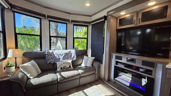 a living room with furniture a flat screen tv and a floor to ceiling window