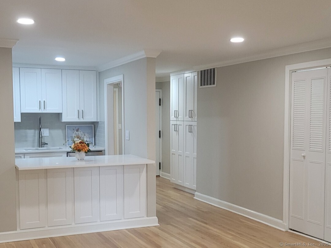 a view of a kitchen with white cabinets and wooden floor