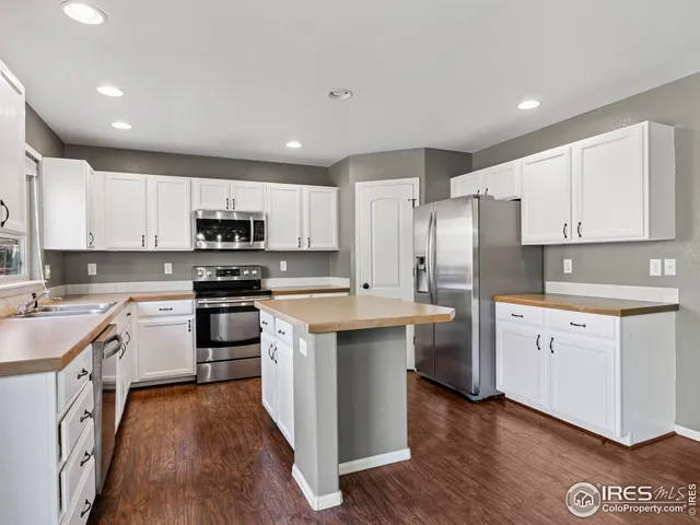 a kitchen with stainless steel appliances white cabinets a sink a stove a refrigerator and microwave