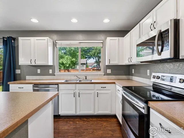 a kitchen with stainless steel appliances granite countertop a sink a stove a microwave a counter space and cabinets