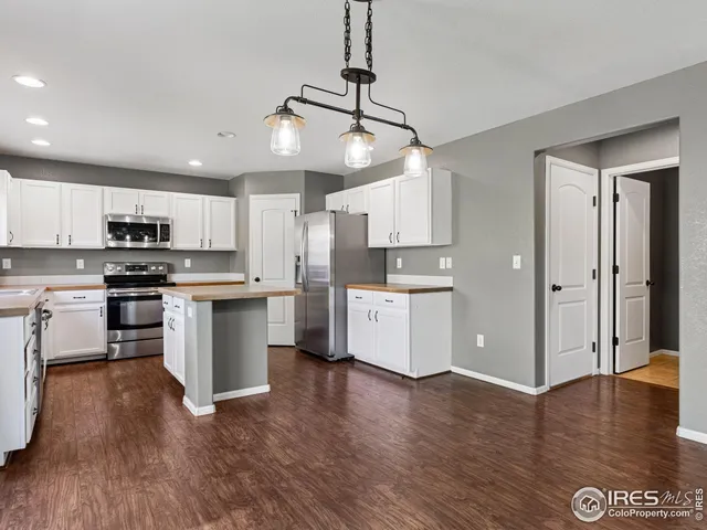 a kitchen with kitchen island white cabinets stainless steel appliances and wooden floor