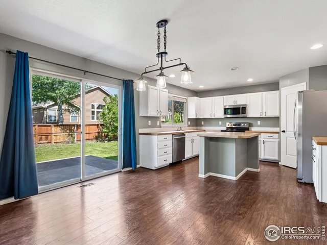 a kitchen with stainless steel appliances granite countertop a refrigerator a sink dishwasher a oven with white cabinets and wooden floor