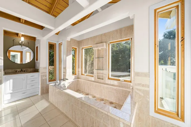 a spacious bathroom with a tub sink and mirror