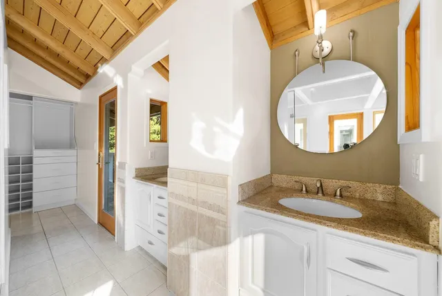a bathroom with a granite countertop sink a mirror and shower