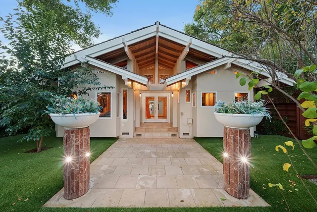a view of a white house next to a yard with big trees