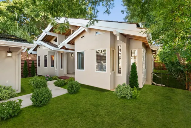 a view of a small house with a small yard and large trees