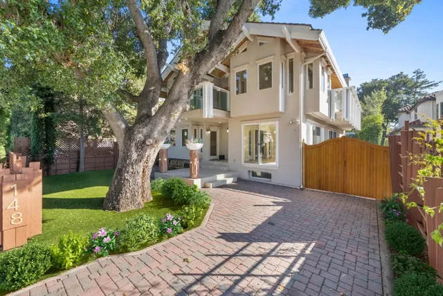 a view of a white house next to a yard with big trees