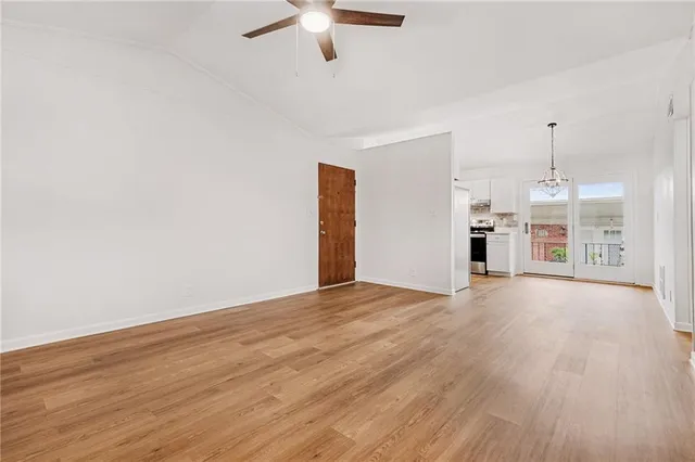 a view of empty room with wooden floor and ceiling fan