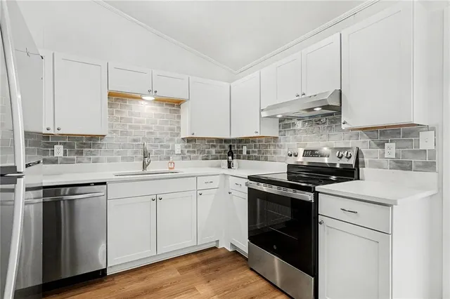 a kitchen with stainless steel appliances granite countertop a sink stove and cabinets