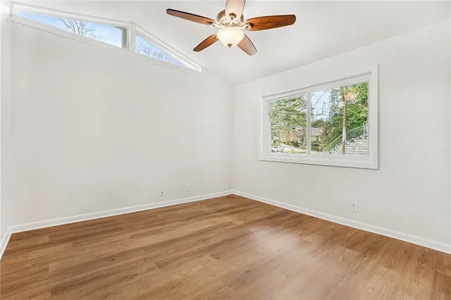 a view of an empty room with window and a ceiling fan