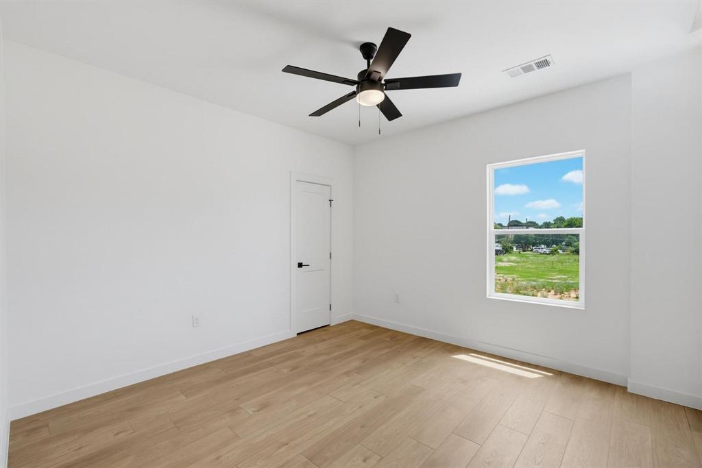 508 South O Connor Road Irving, TX 75060 - Photo 9 of 21 Spacious room featuring wood-finish flooring, a contemporary ceiling fan with integrated lighting, a single window, and a white interior door with matte black hardware
