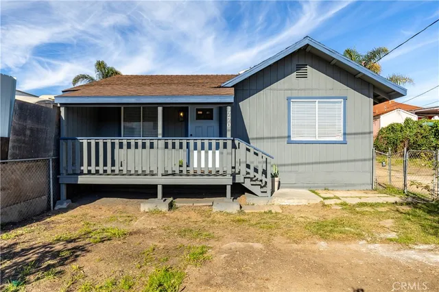 a view of a house with wooden fence and a yard