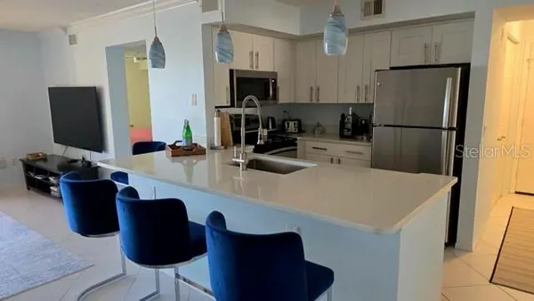 a kitchen with a refrigerator a stove a sink and chairs