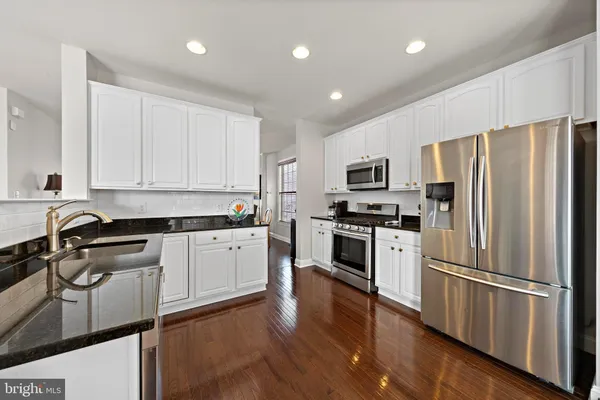 a kitchen with granite countertop stainless steel appliances a refrigerator a stove top oven a sink and cabinets