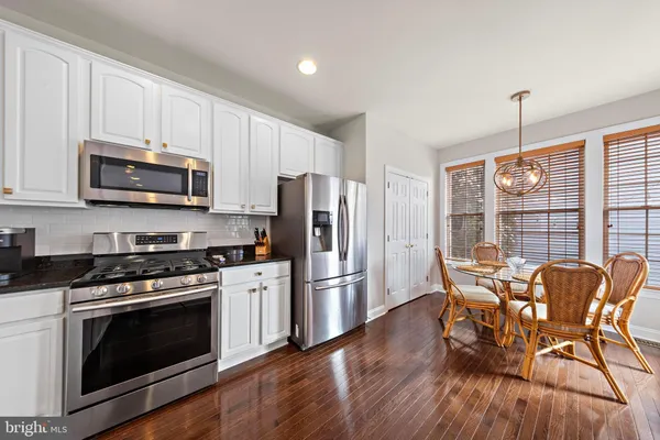 a kitchen with stainless steel appliances a stove a refrigerator microwave and wooden floors