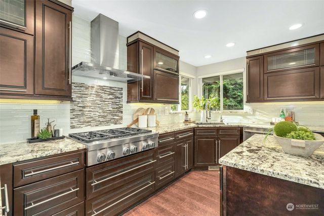 a kitchen with stainless steel appliances granite countertop wooden cabinets and a stove top oven