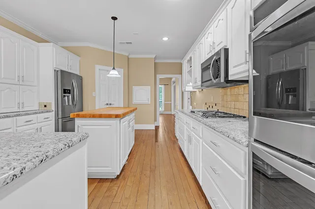 a large kitchen with granite countertop a sink and dishwasher a stove top oven with wooden floor