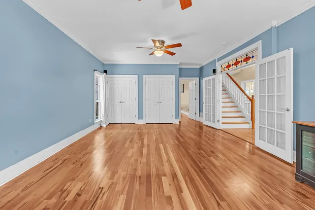 a view of an empty room with wooden floor and stairs