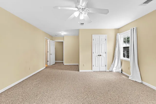 an empty room with closet and a ceiling fan