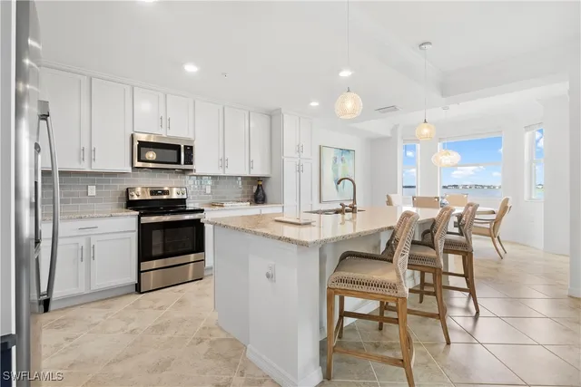 a kitchen with stainless steel appliances kitchen island granite countertop a stove top oven a sink a dining table and chairs