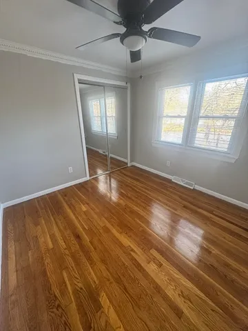 a view of an empty room with window and wooden floor