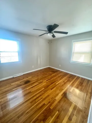 a view of a room with wooden floor and a ceiling fan