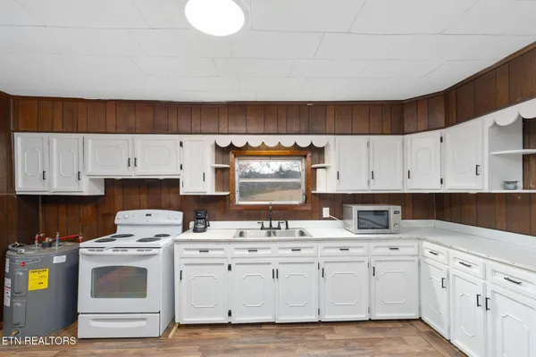 a kitchen with granite countertop a sink a stove and cabinets