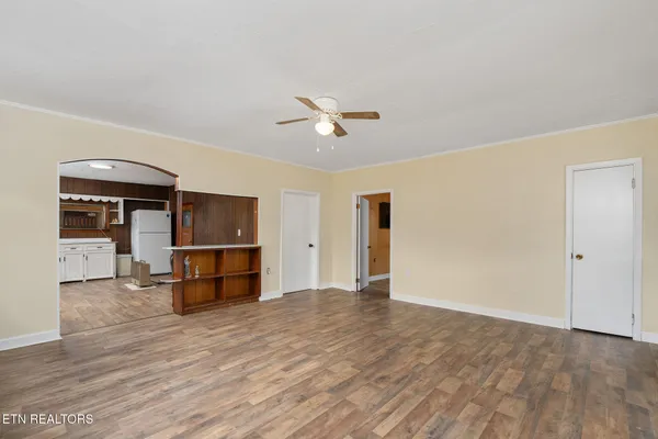an empty room with wooden floor and a ceiling fan