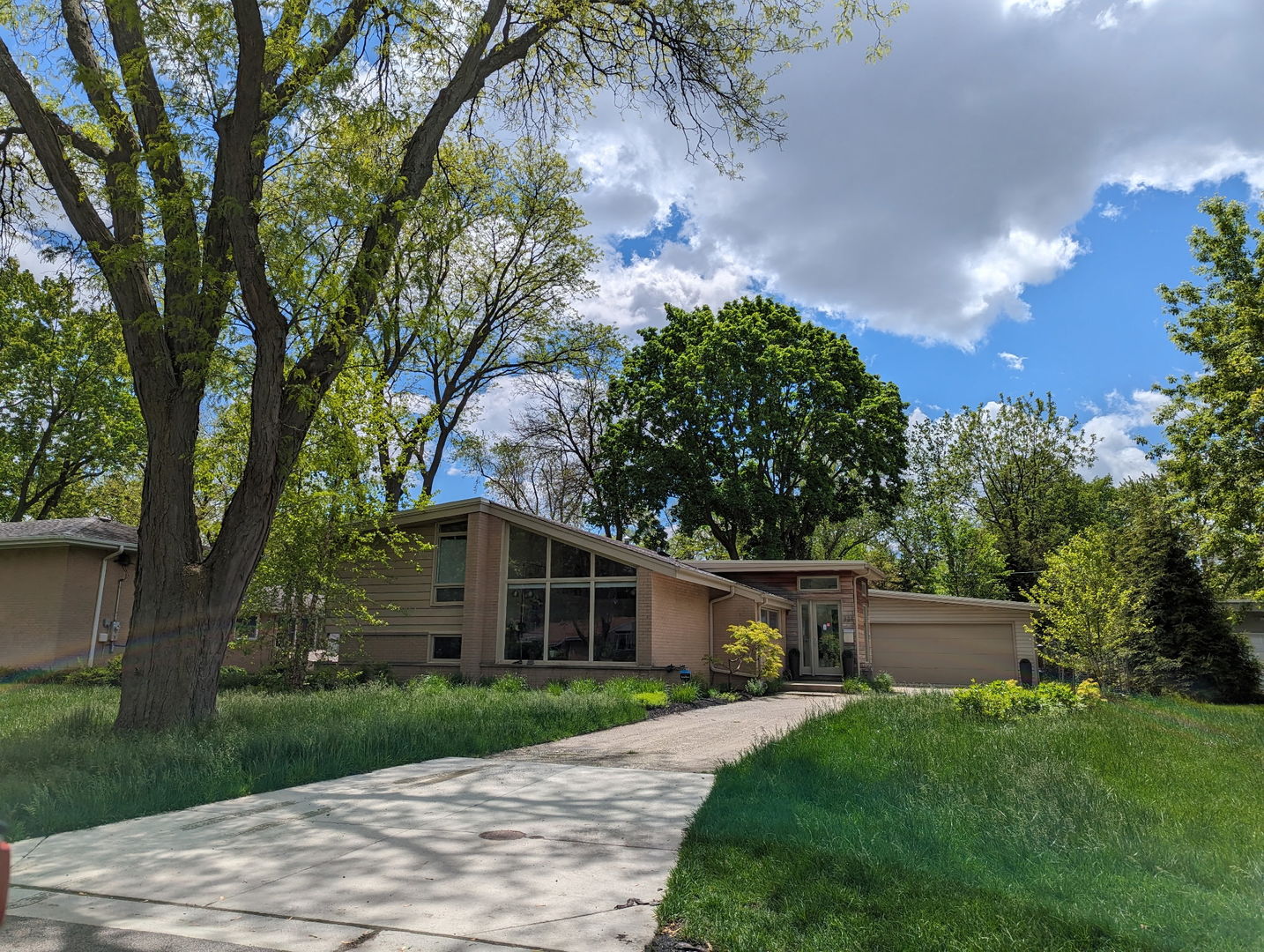 a front view of a house with a garden and trees