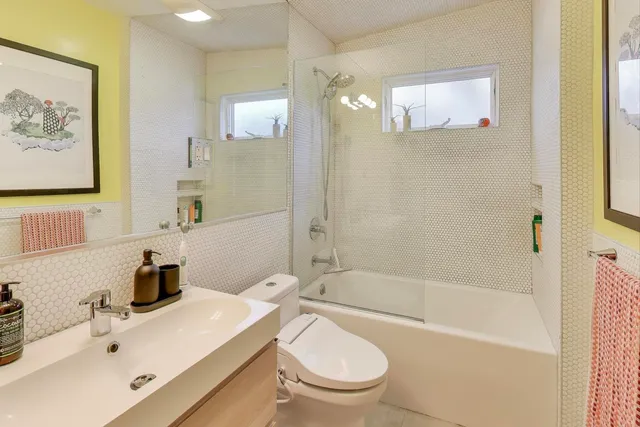a bathroom with a bathtub shower sink mirror vanity and toilet